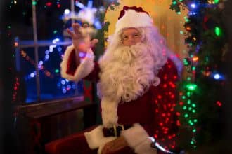 santa claus sitting beside lit tree