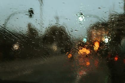 Road in modern city street with lights through car window in rainy weather