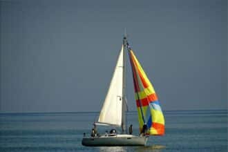 Gray and White Sail Boat With 5 Person Riding on the Middle of the Body of Water